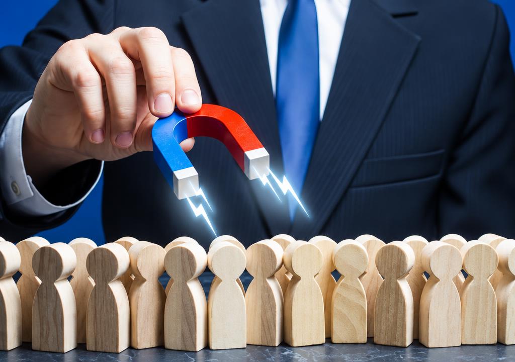 A businessman attracting wooden customer figures with a magnet